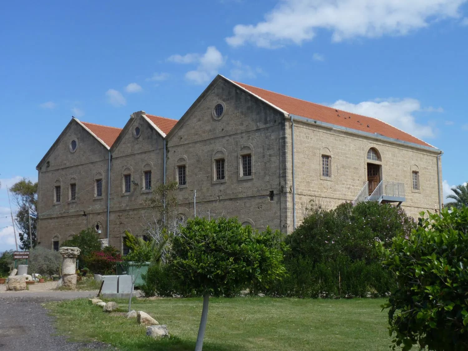 The stone building with a red tiled roof that houses the Mizgaga museum at Nahsholim, among trees