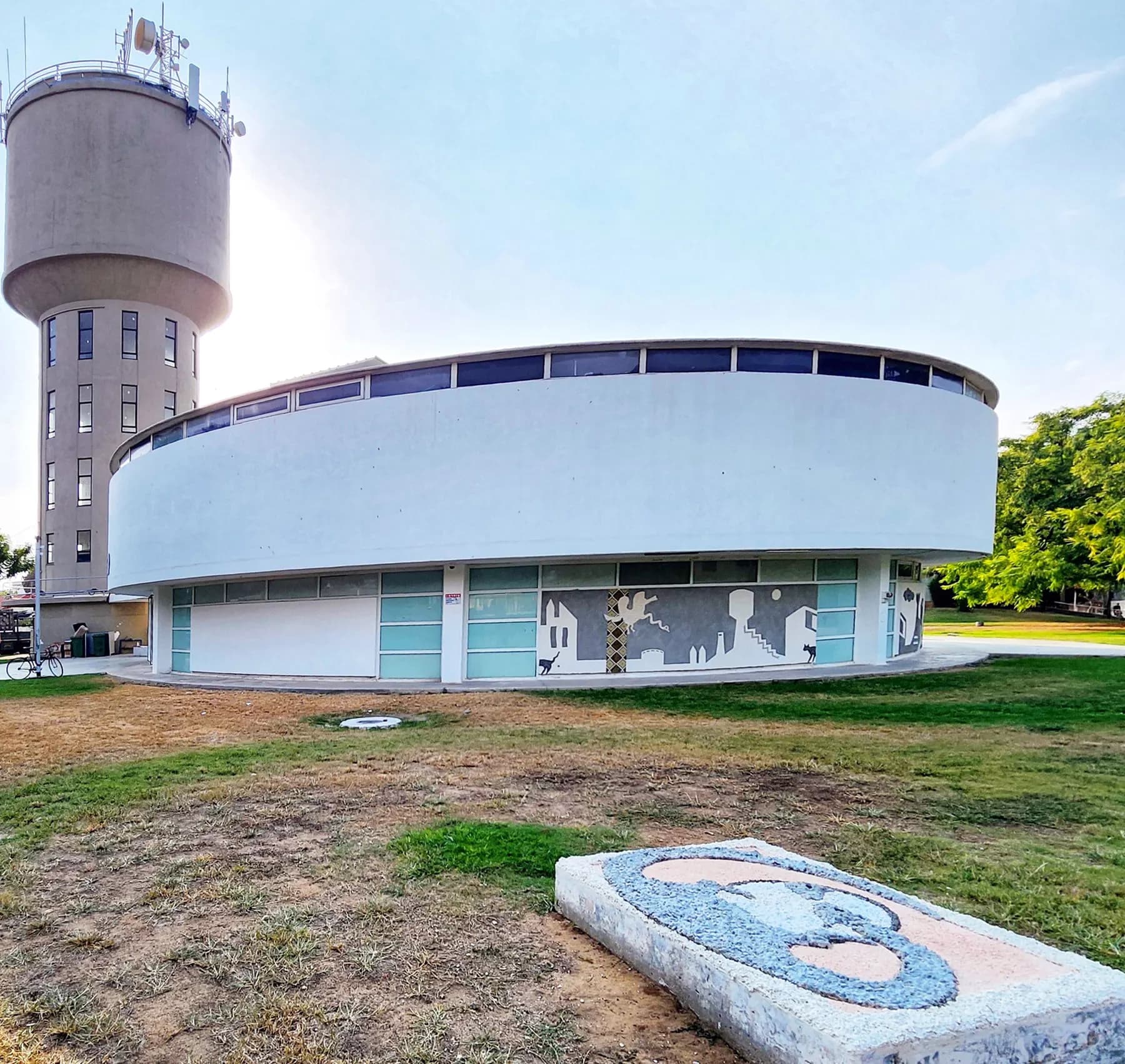 The round white building of MOBY, the museums of Bat Yam, beside a water tower