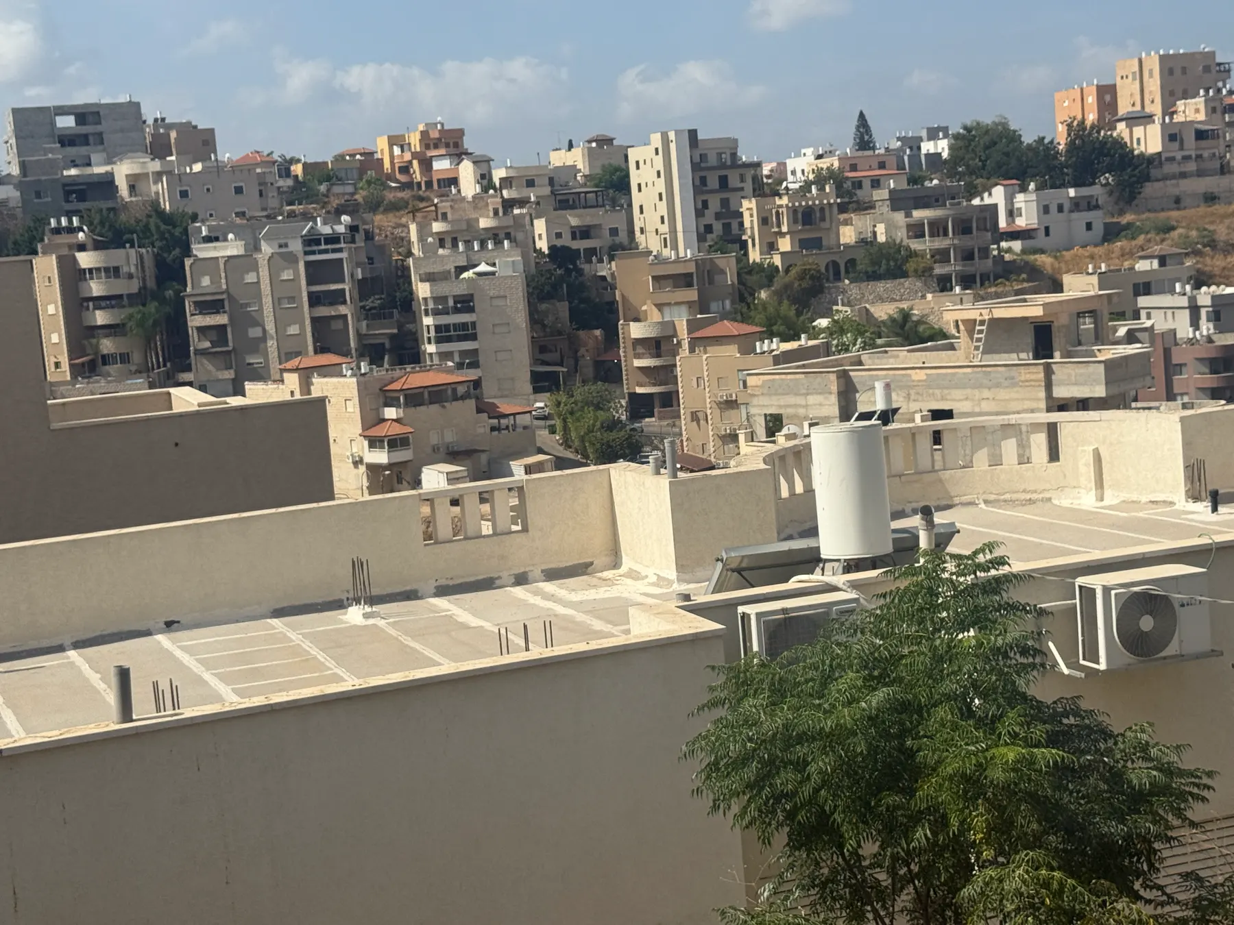 Apartment buildings and houses climbing a hillside in Abu Snan, seen over nearby rooftops.