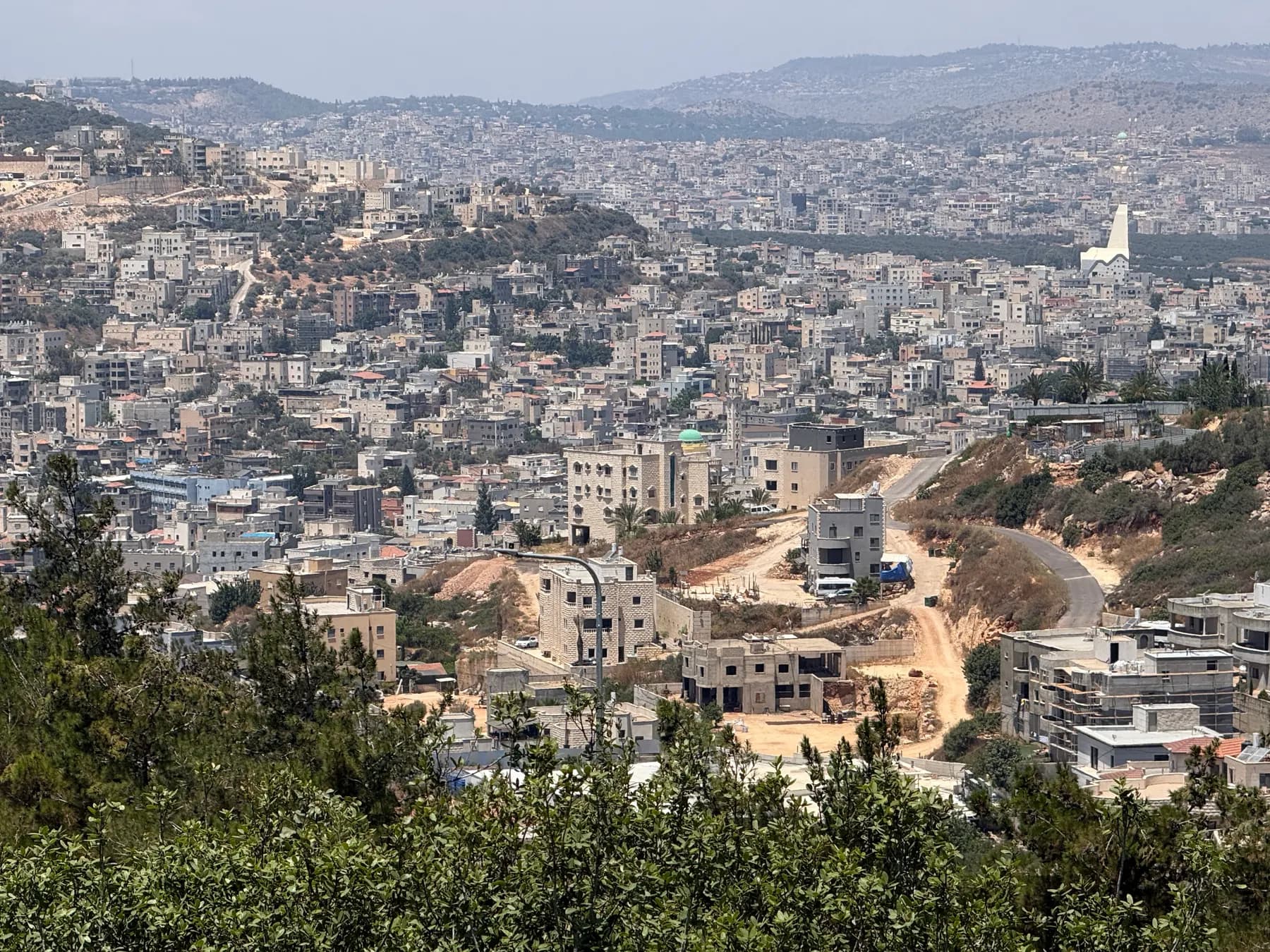 A view over the houses of Arraba spread across the valley, with wooded hills behind.