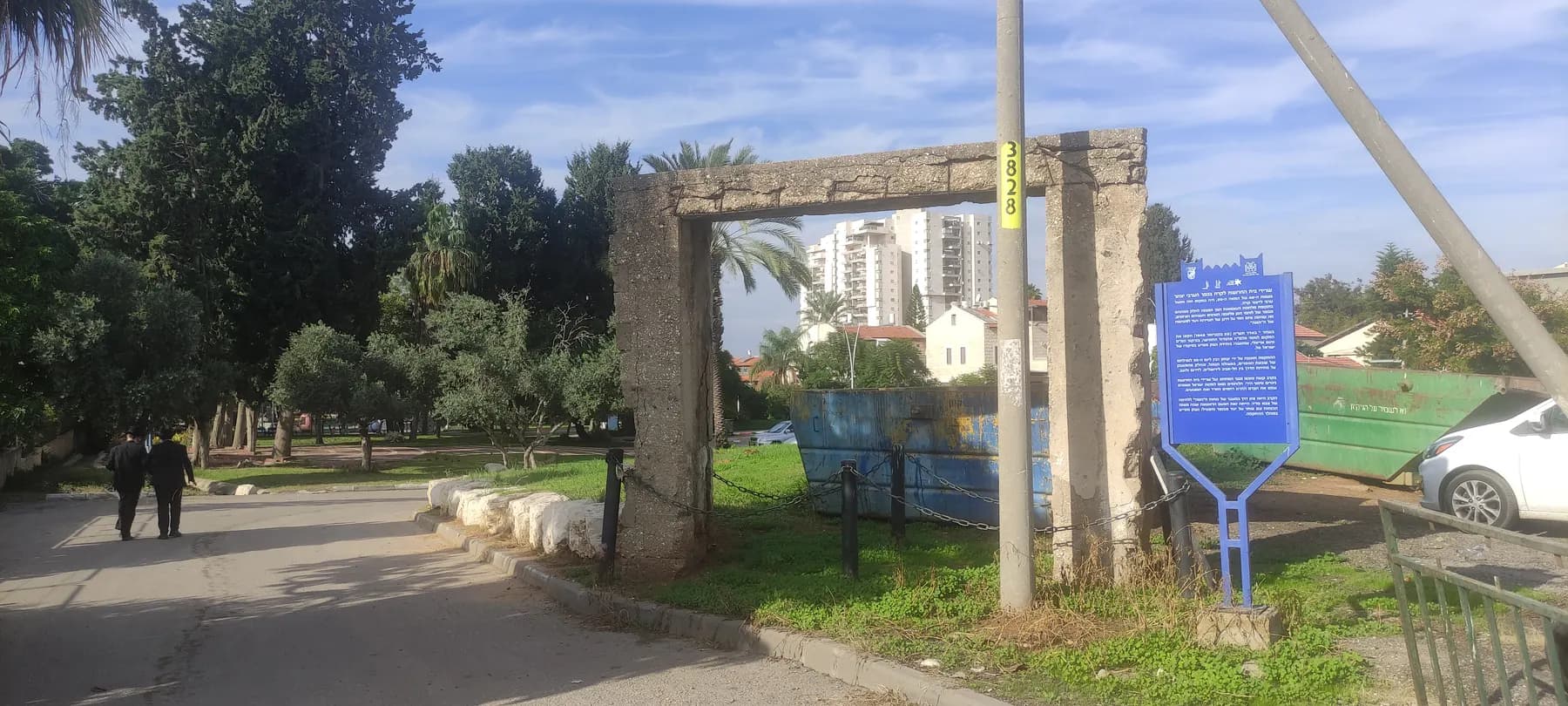 The concrete frame left from the old ice factory in Azor, beside a lawn and a heritage sign, with apartment towers behind.