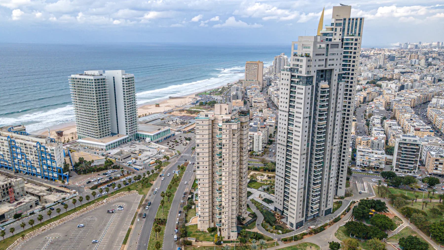 An aerial view of residential towers along the Bat Yam seafront, with the beach and the sea beside them.
