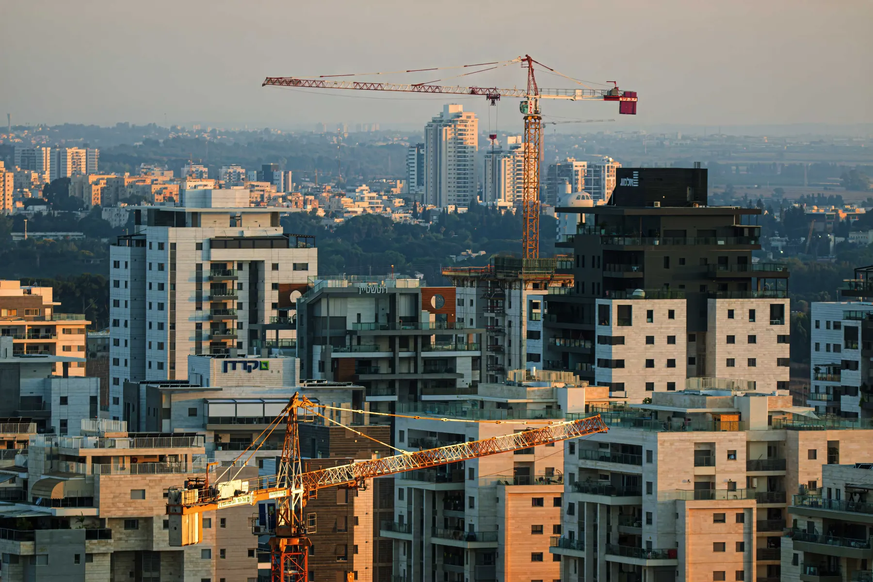 New apartment towers and construction cranes in Be'er Ya'akov, with more towers in the haze behind.