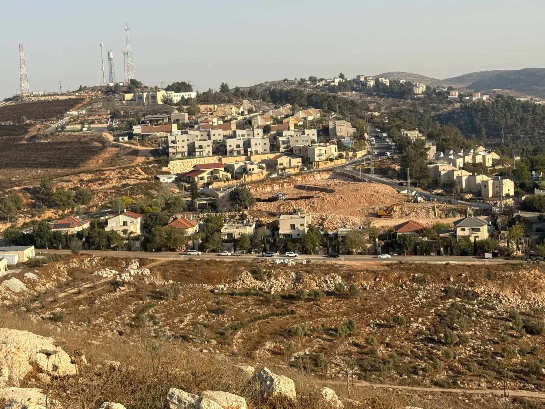 Houses of Elon Moreh spread along a hillside above rocky slopes, with antenna masts on the ridge.