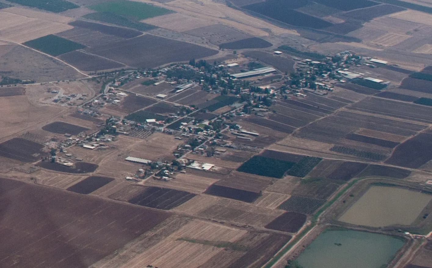 מבט מהאוויר על הזורעים, בתיה ומבני המשק שלה בין עצים לאורך כמה דרכים, מוקפים בשדות חומים.