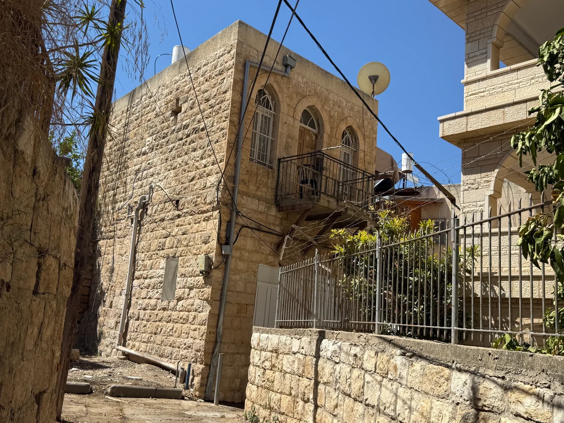 An old stone house with arched windows and an iron balcony in the old core of Kafr Yasif.