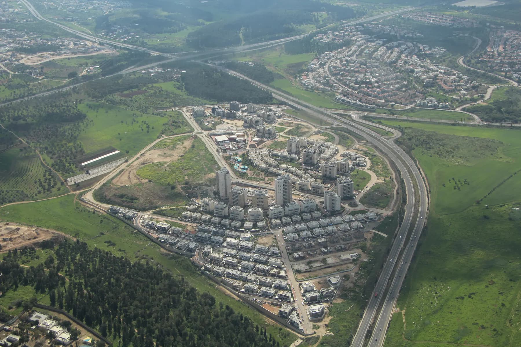An aerial view of the Givat Alonim neighbourhood of Kiryat Ata beside Highway 79, among green fields.
