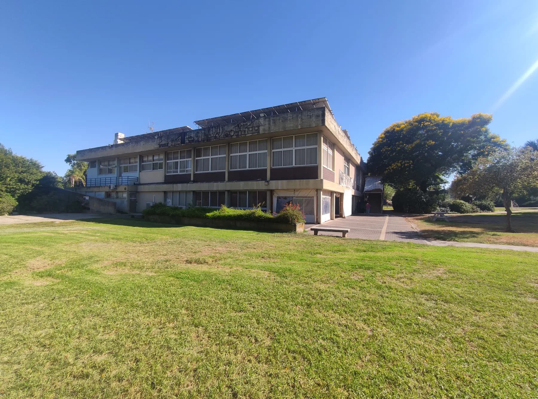 The dining hall of Mahanayim, a two-storey building with long bands of windows, seen across a wide lawn with large trees beside it.
