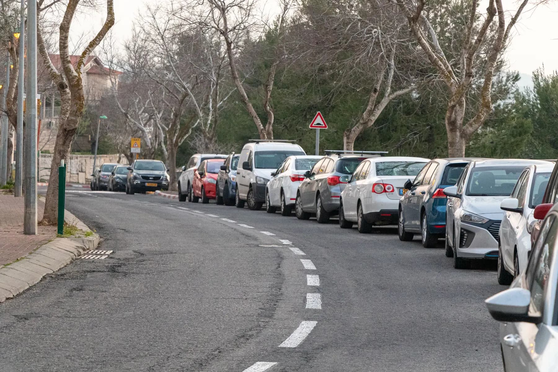 Cars parked along a curving, tree-lined stretch of Hermon Street in Mevaseret Zion.