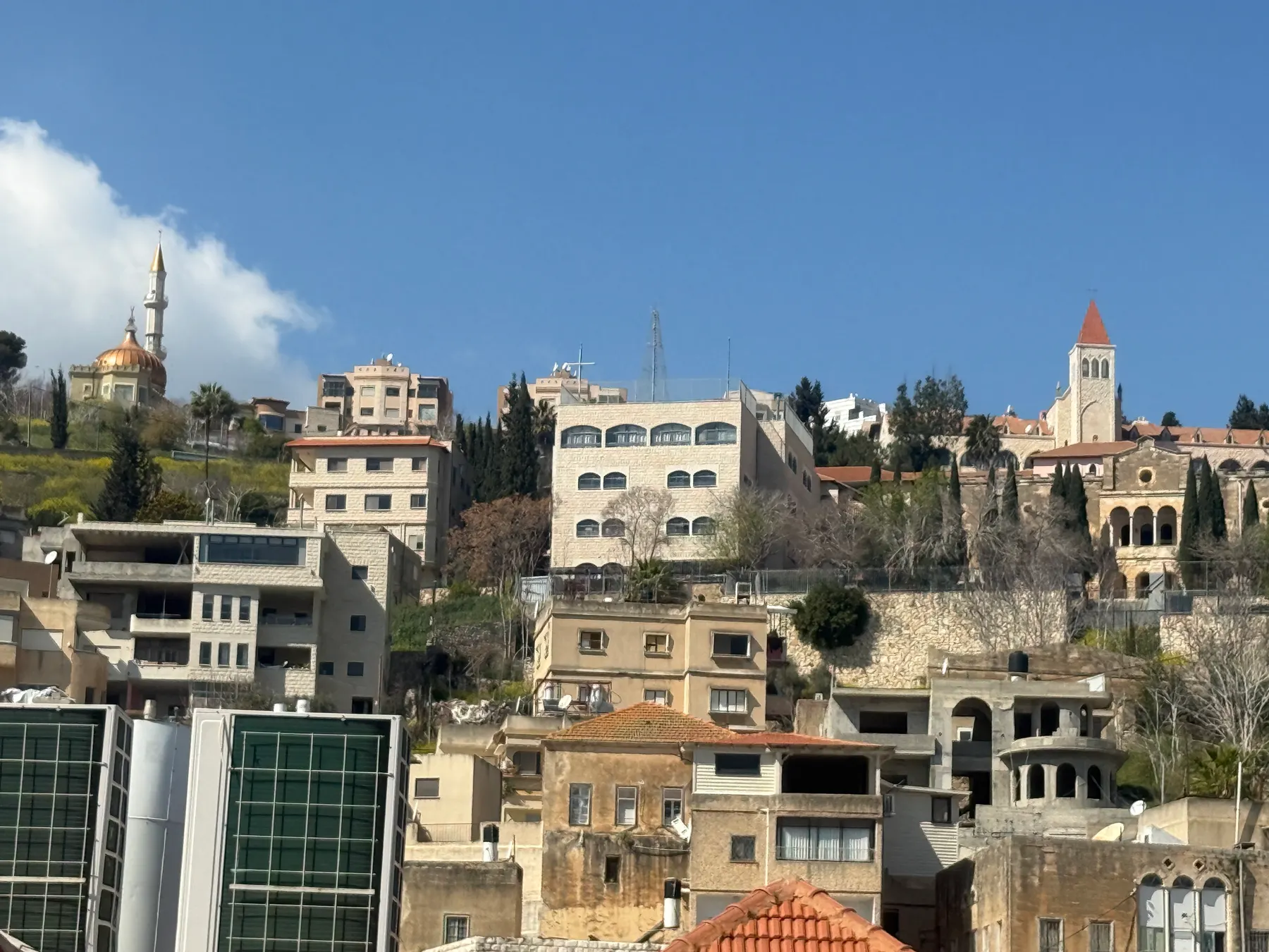 Houses on a hillside in Nazareth, with a church bell tower and a mosque minaret on the skyline.