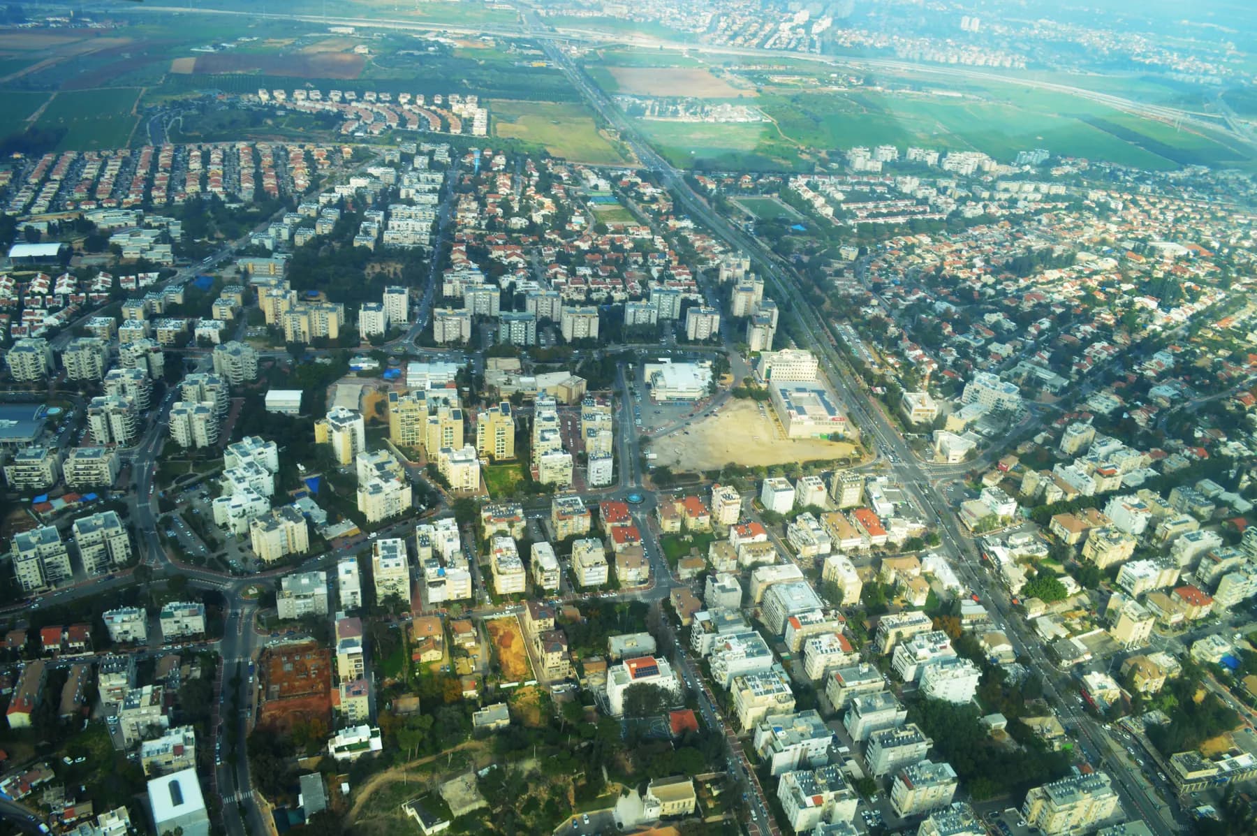 An aerial view of central Ness Ziona, with apartment blocks, houses and a main road.