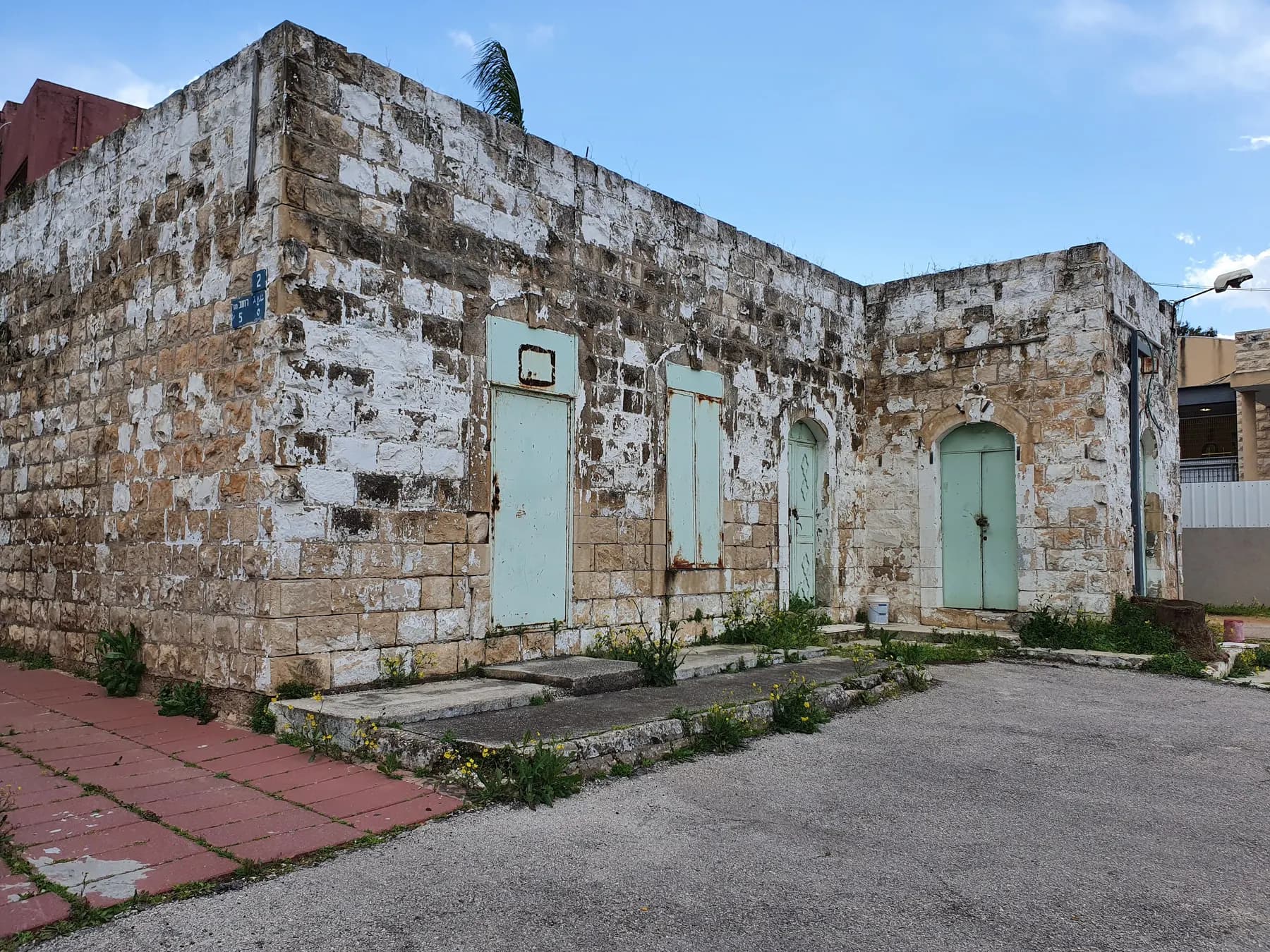 The old stone building of the first school in Qalansawe, with pale green doors and shutters.