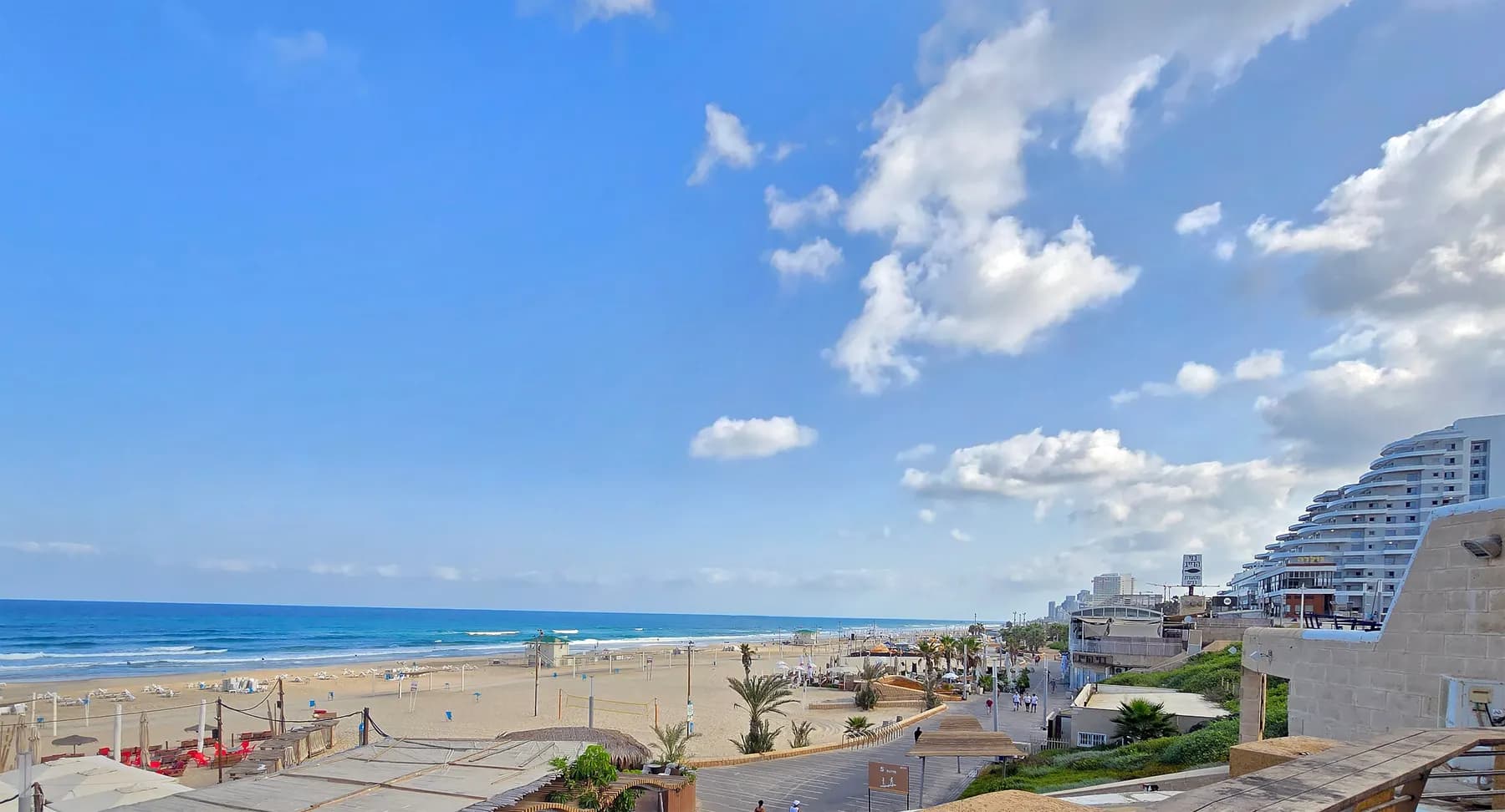 Rishon LeZion's beach and seafront promenade under a blue sky, with the sand running north along the sea