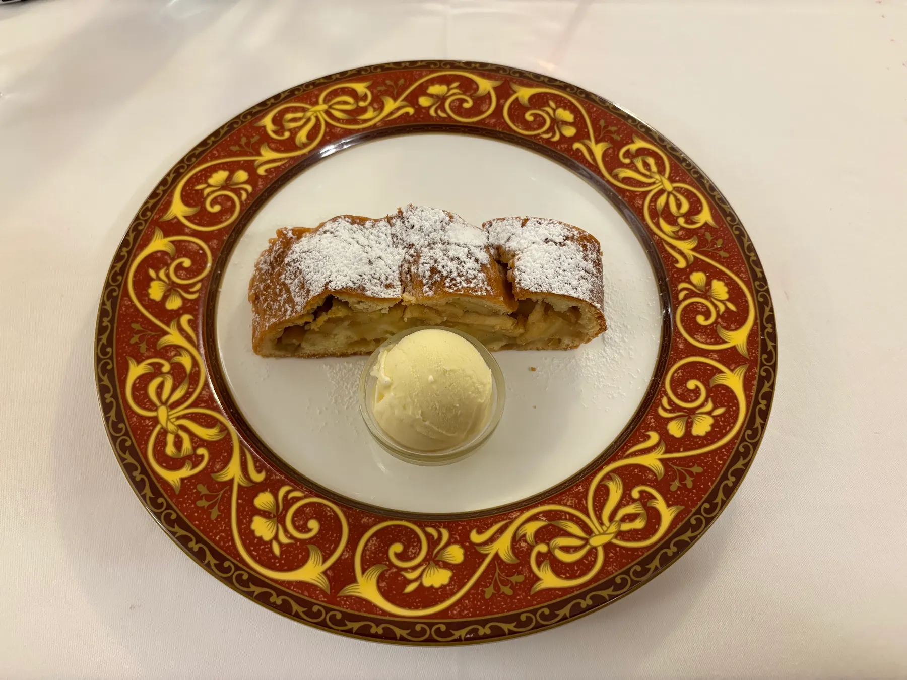 A slice of apple strudel with a scoop of vanilla ice cream