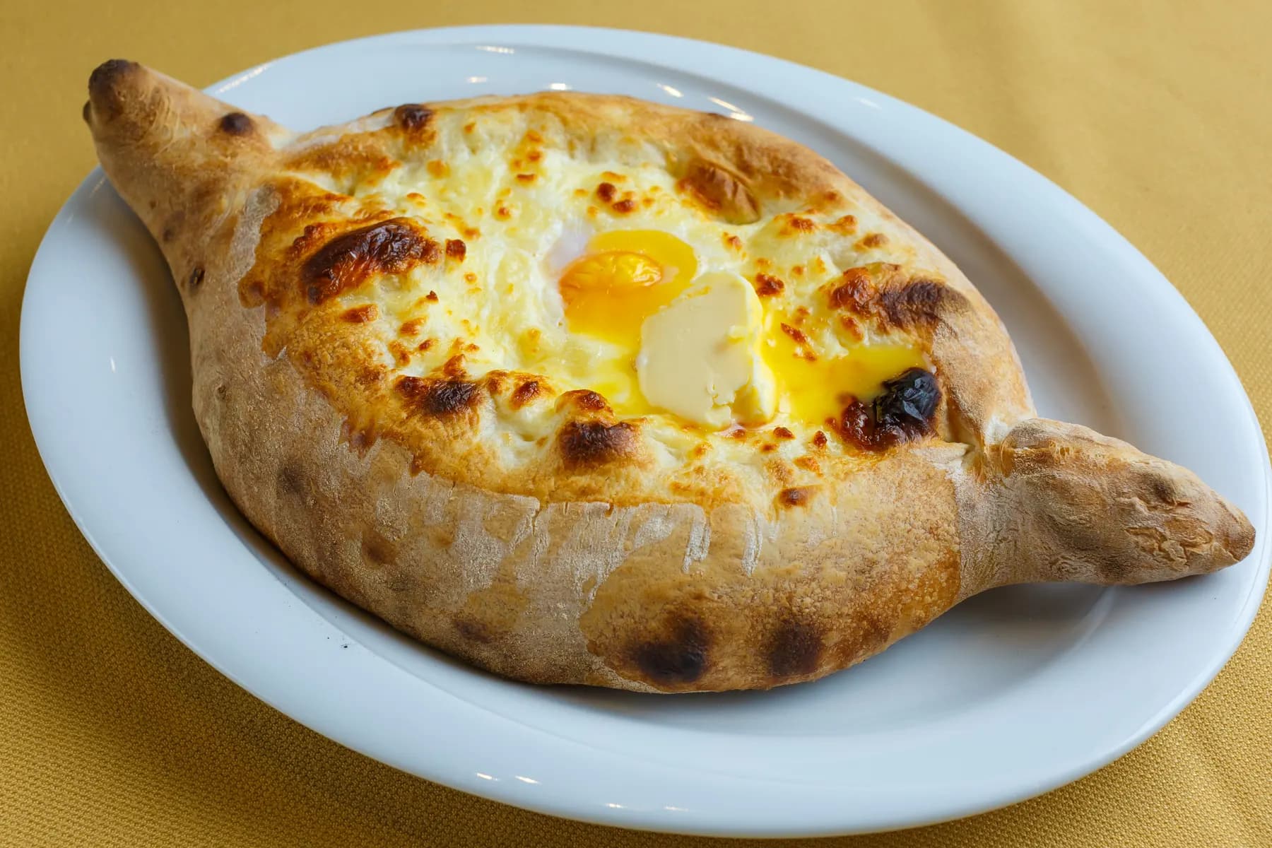 An Adjarian khachapuri: a boat of baked bread filled with melted cheese, an egg yolk and a knob of butter