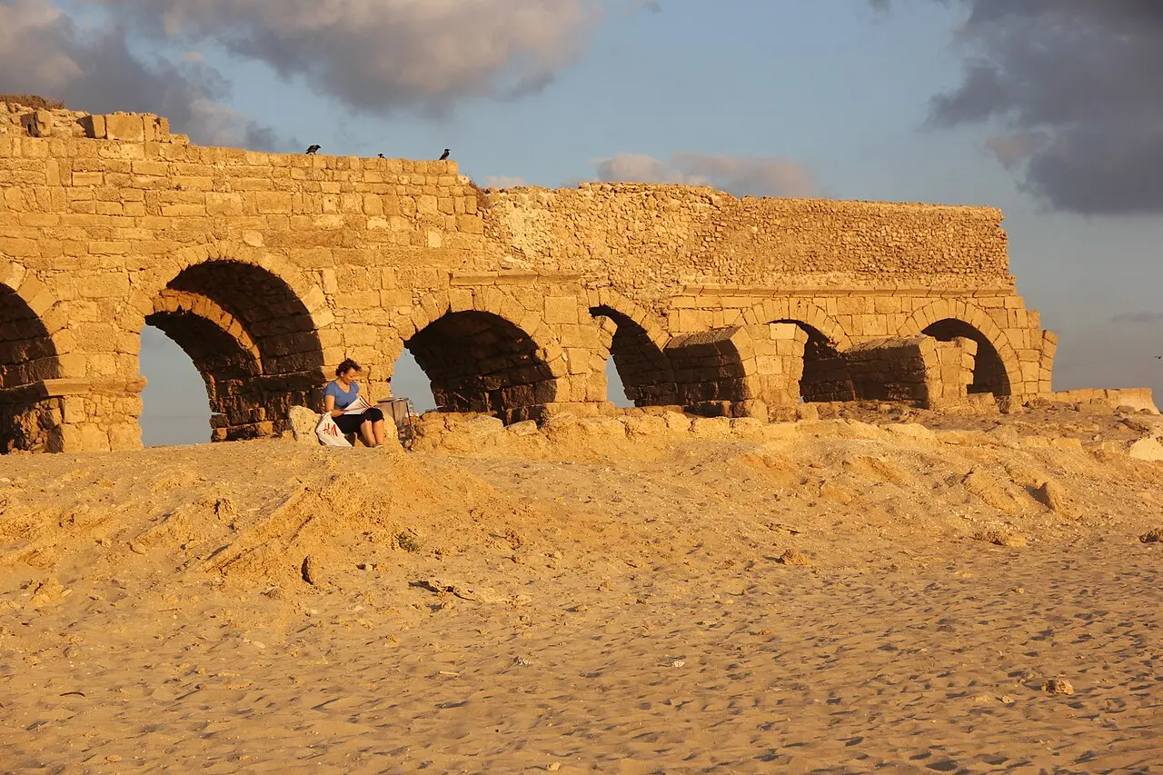 The aqueduct's arches at the back of the sand at Aqueduct Beach, late in the day
