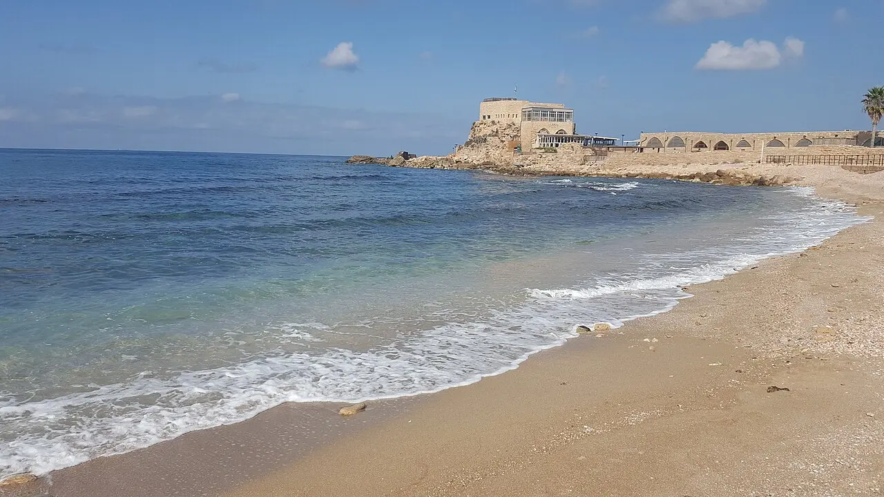 The shore at Caesarea with the old port on its promontory in the distance
