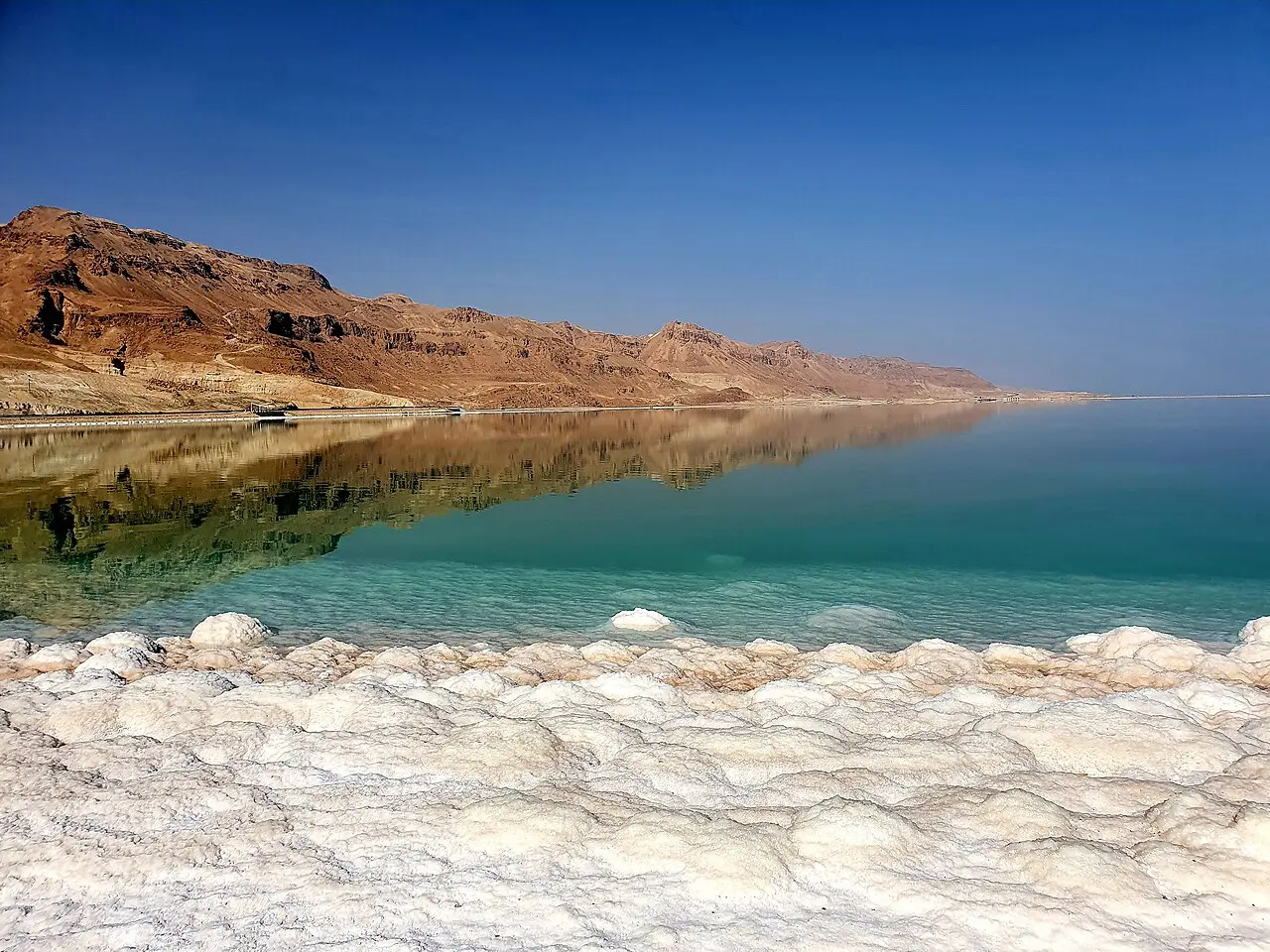 Salt crusting the shoreline at Ein Bokek, the cliffs reflected in the still water