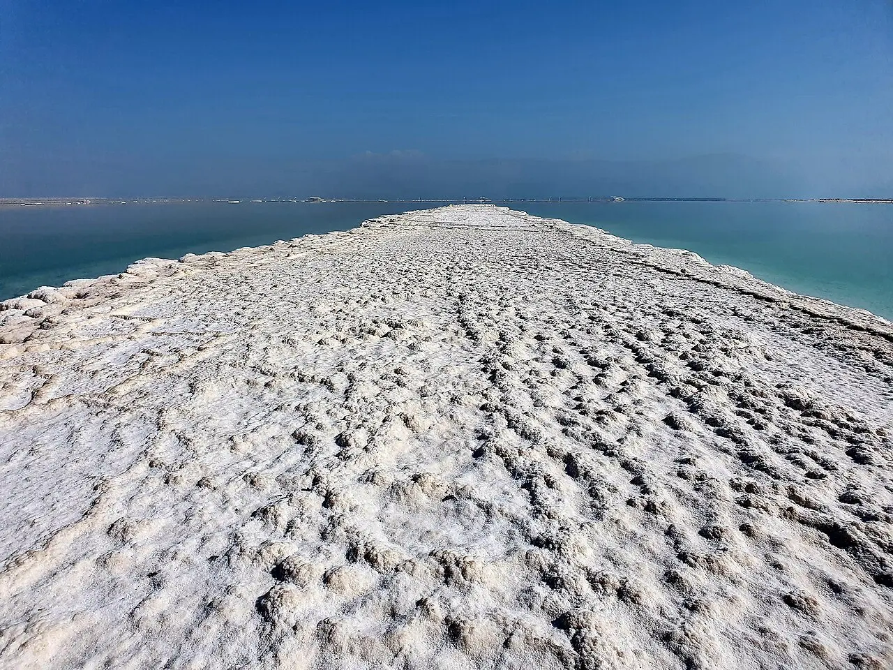 A ridge of crusted salt running out into the Dead Sea at Ein Bokek