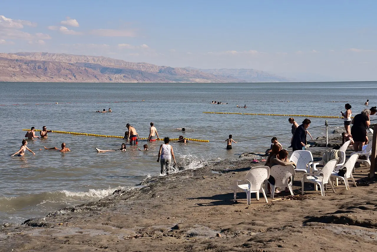 Bathers at the water's edge at Kalia Beach, the hills of Jordan across the Dead Sea