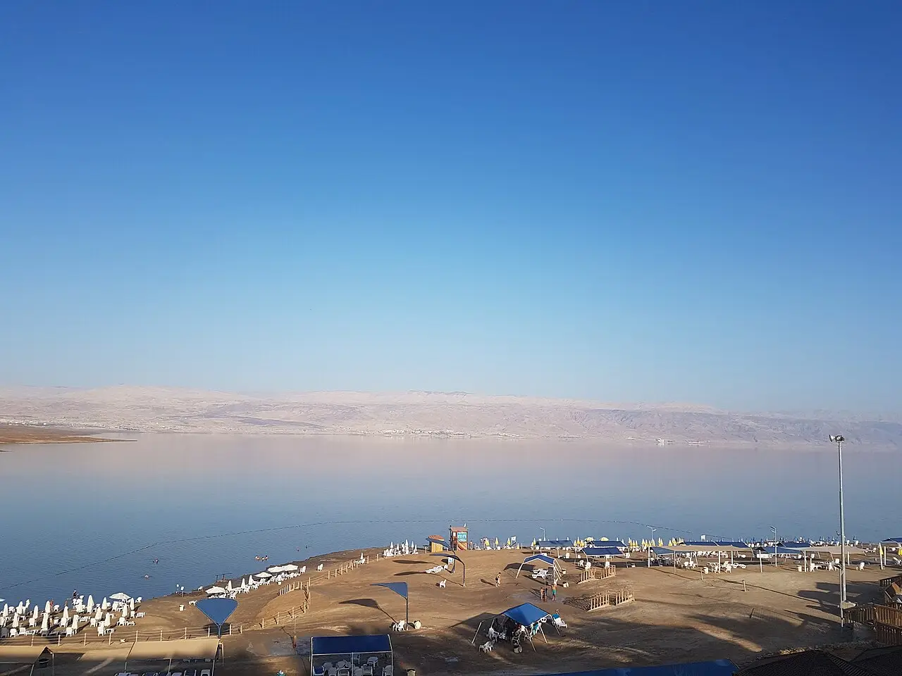 The shore at Kalia Beach from above, the Dead Sea flat and pale beyond it