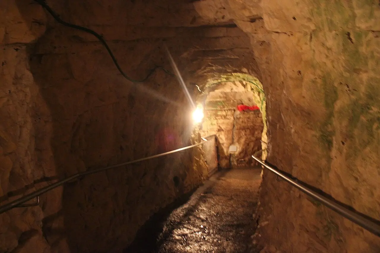 A rock-cut tunnel with a handrail inside the cliff at Rosh Hanikra