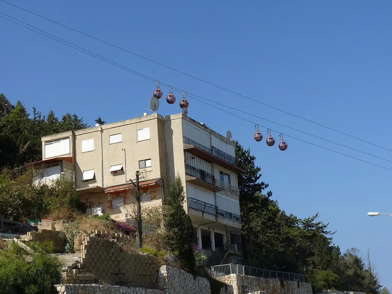 The cable car's cabins passing above a hillside apartment block in Haifa
