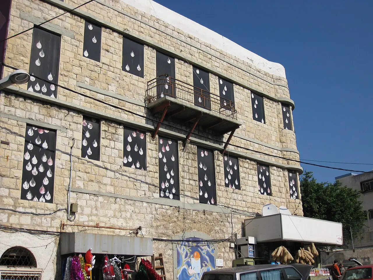 An art installation of white shapes fixed around the windows of a stone house in Wadi Nisnas