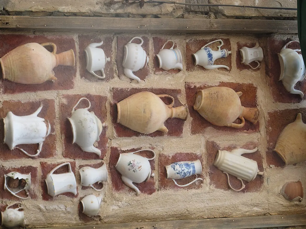 Clay jugs and white teapots set into a wall as street art in Wadi Nisnas