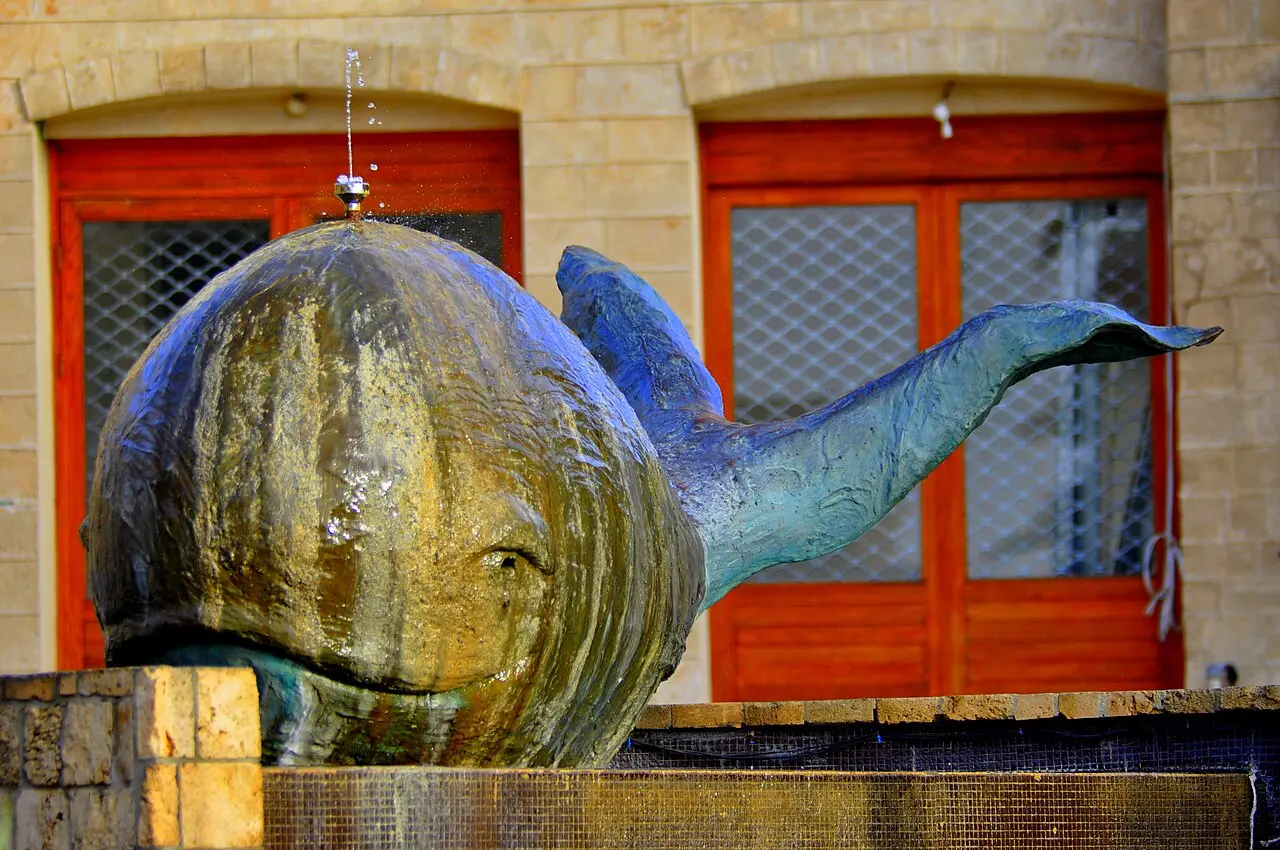 Ilana Goor's bronze whale sculpture in front of red-framed doors in Old Jaffa