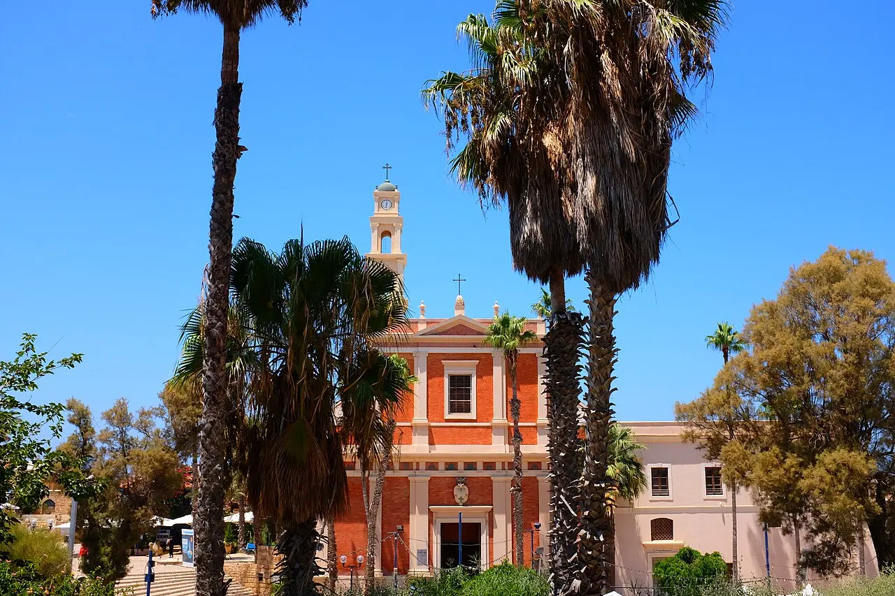 The orange front of St Peter's Church in Jaffa, framed by palm trees