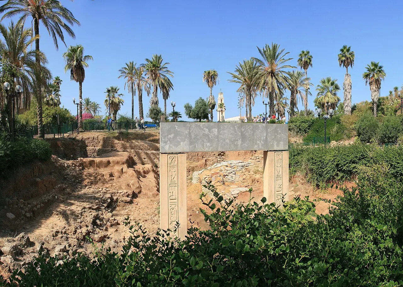 The excavation pit and the gate replica among the palms of the garden