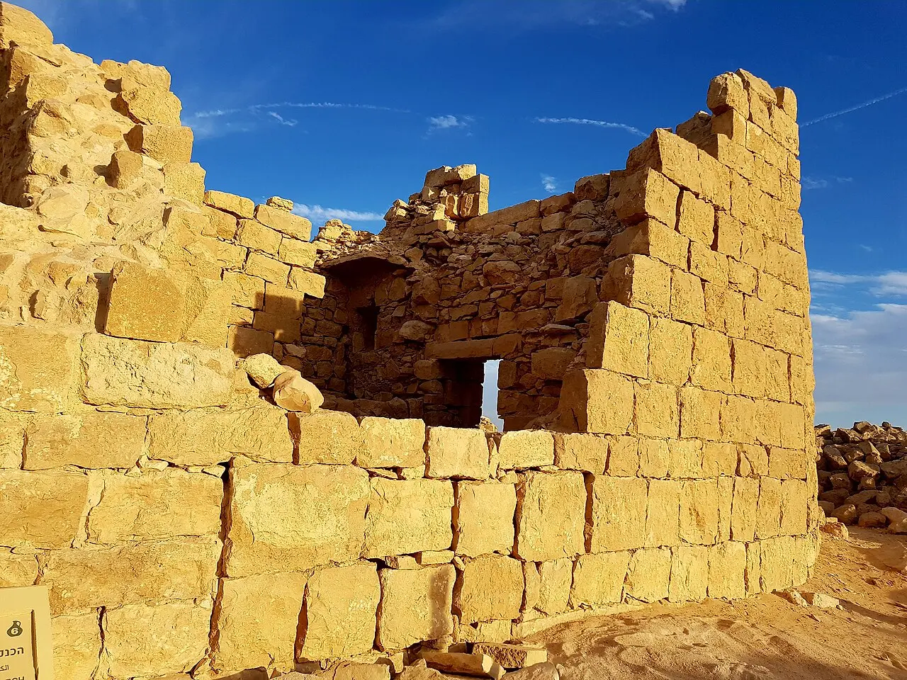 A standing wall of dressed stone at Shivta, lit by low sun