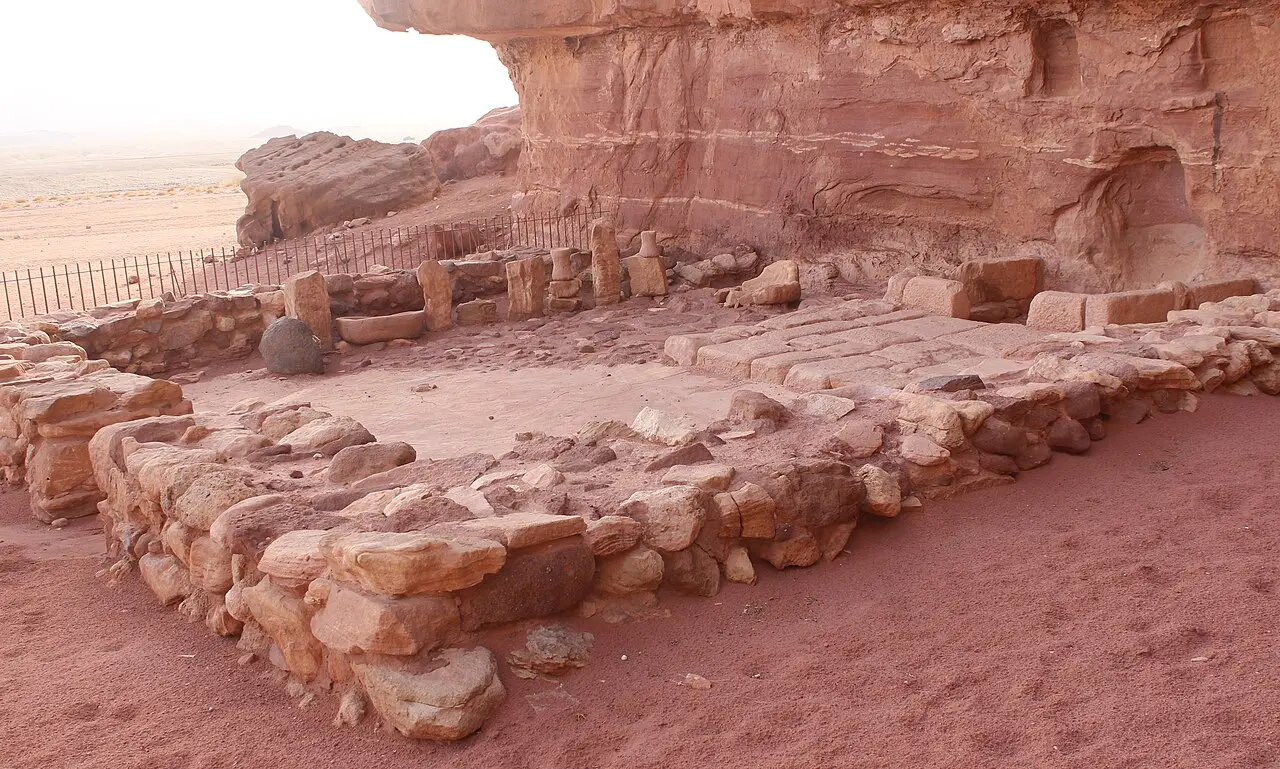 The low stone walls of the Hathor temple at the foot of the sandstone cliff in Timna Park