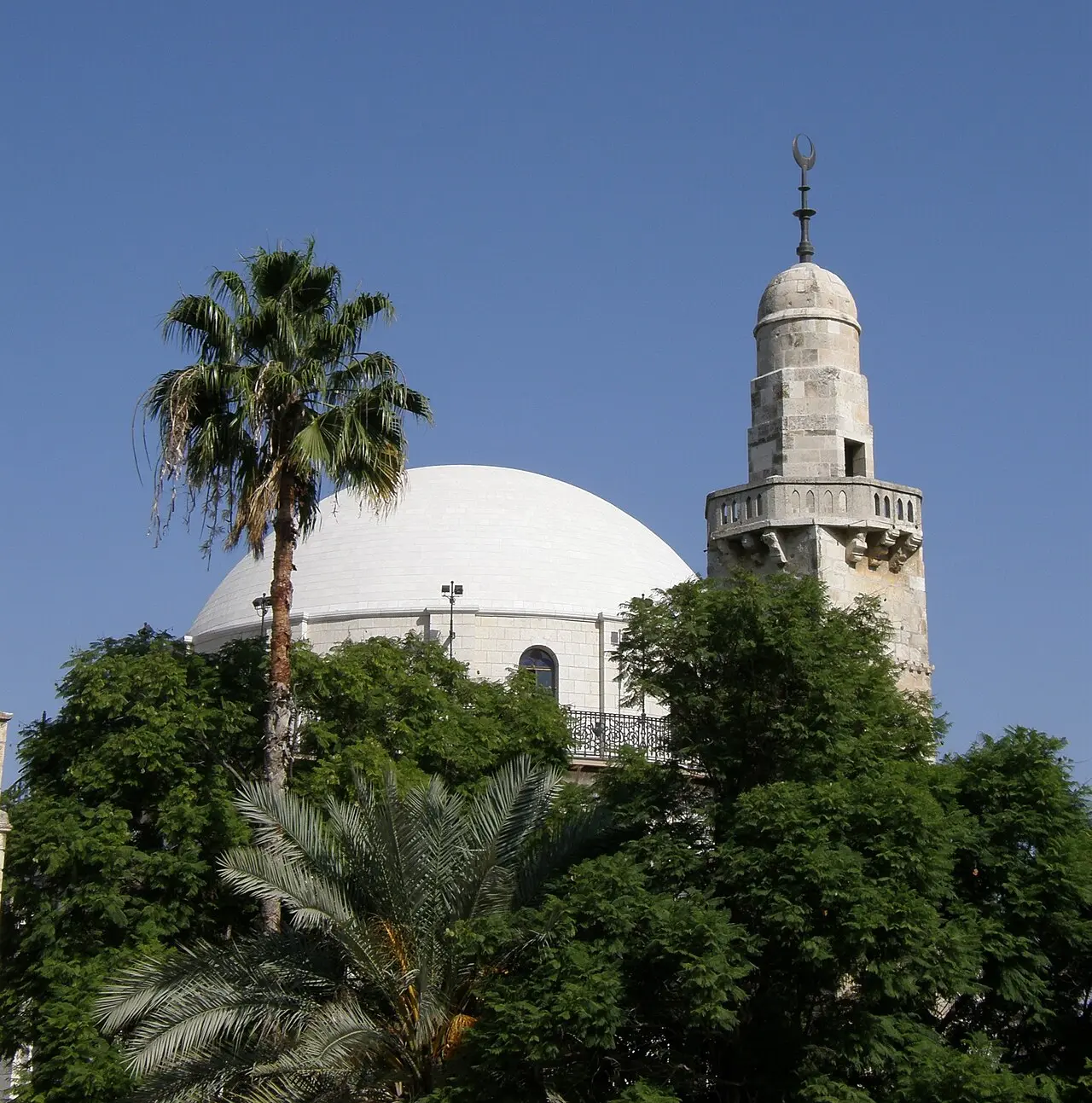 The Hurva's dome beside the neighbouring minaret, above the trees of the square