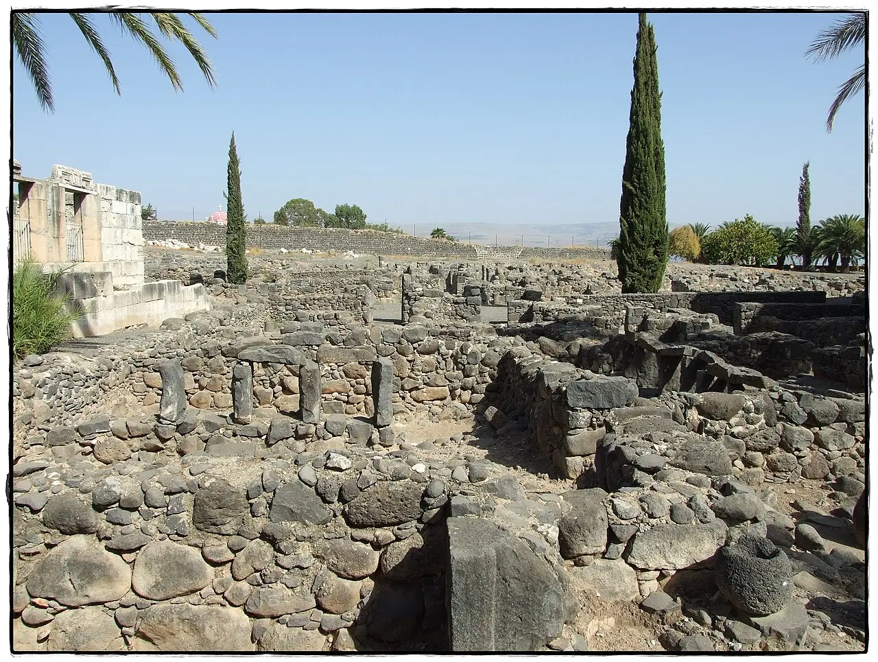 Basalt house walls of the ancient town at Capernaum, the synagogue beyond