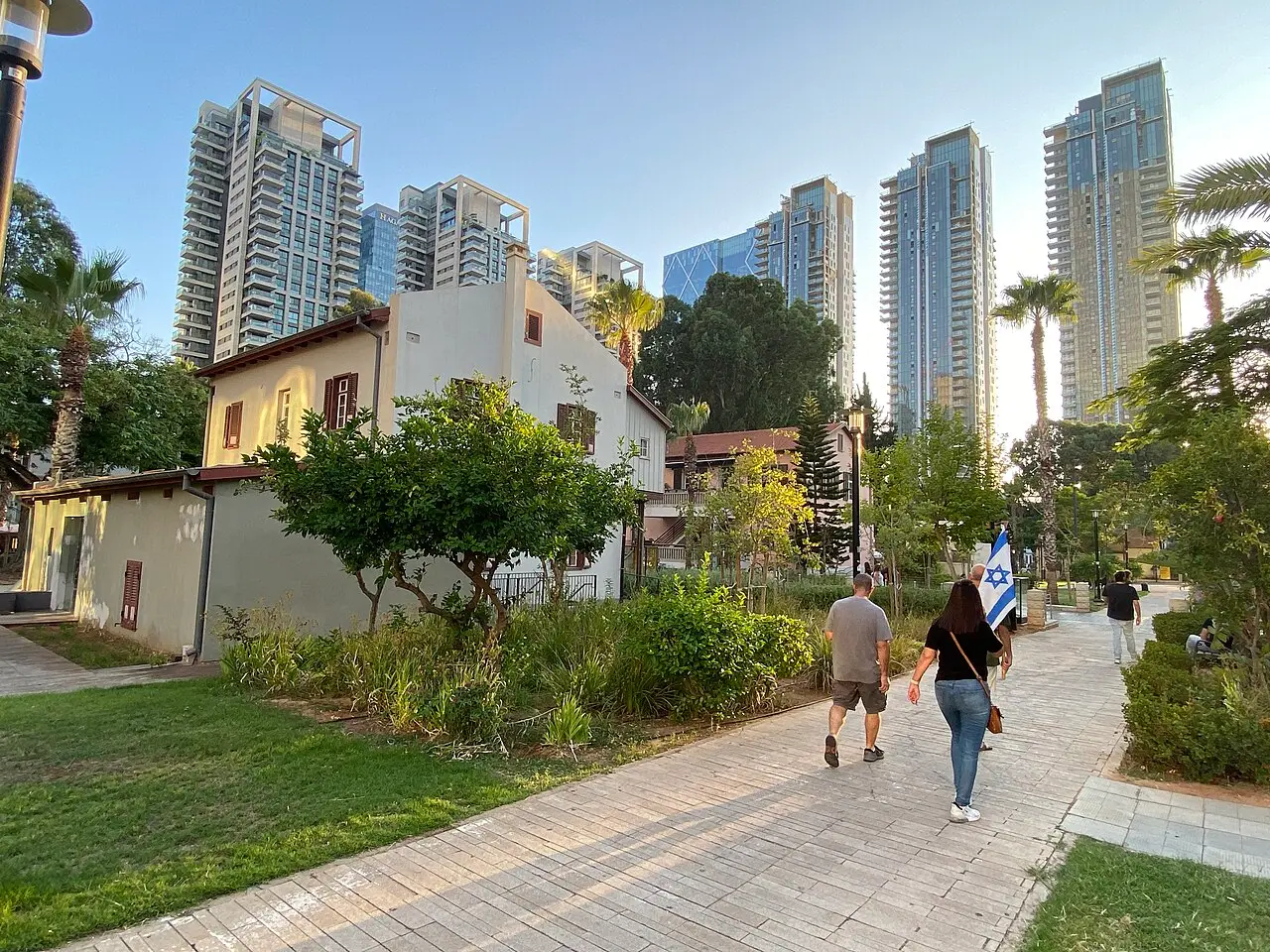 A path past a restored Templer house in Sarona, residential towers above it