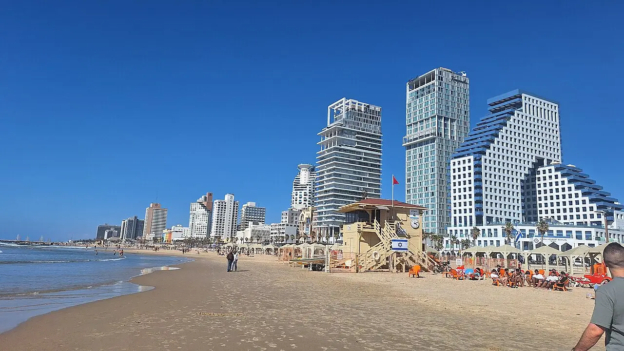 A lifeguard tower on the sand with Tel Aviv's towers behind it