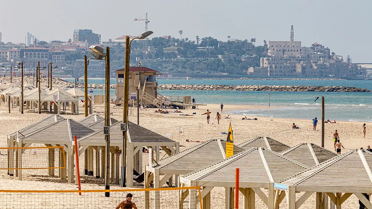 Shade shelters and a lifeguard hut on a Tel Aviv beach, Old Jaffa on the headland behind